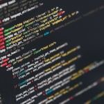 A line of code against a glass monitor showing organized lines with unique colored formats.