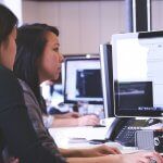 a woman sitting at a desk looking at a laptop